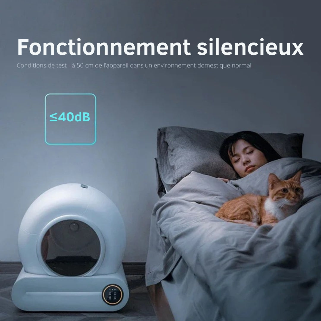 image de la litière autonettoyante ronde blanche dans une chambre à coté d'un lit avec une femme et un chat qui dorment