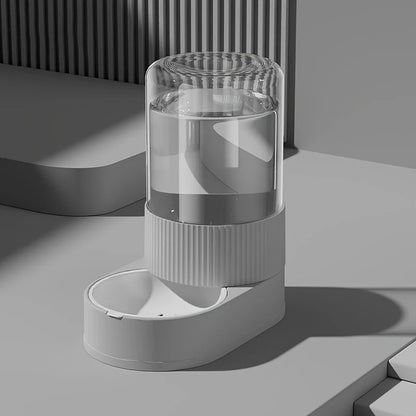 Vue de profil d'un abreuvoir automatique gris design assorti au distributeur croquettes chat de la collection. Le visuel montre le réservoir d'eau transparent par gravité et le socle texturé strié moderne. Cet abreuvoir complète parfaitement un distributeur croquettes pour une autonomie sans électricité. Idéal avec un distributeur croquettes chien miniature pour un coin repas urbain et épuré.