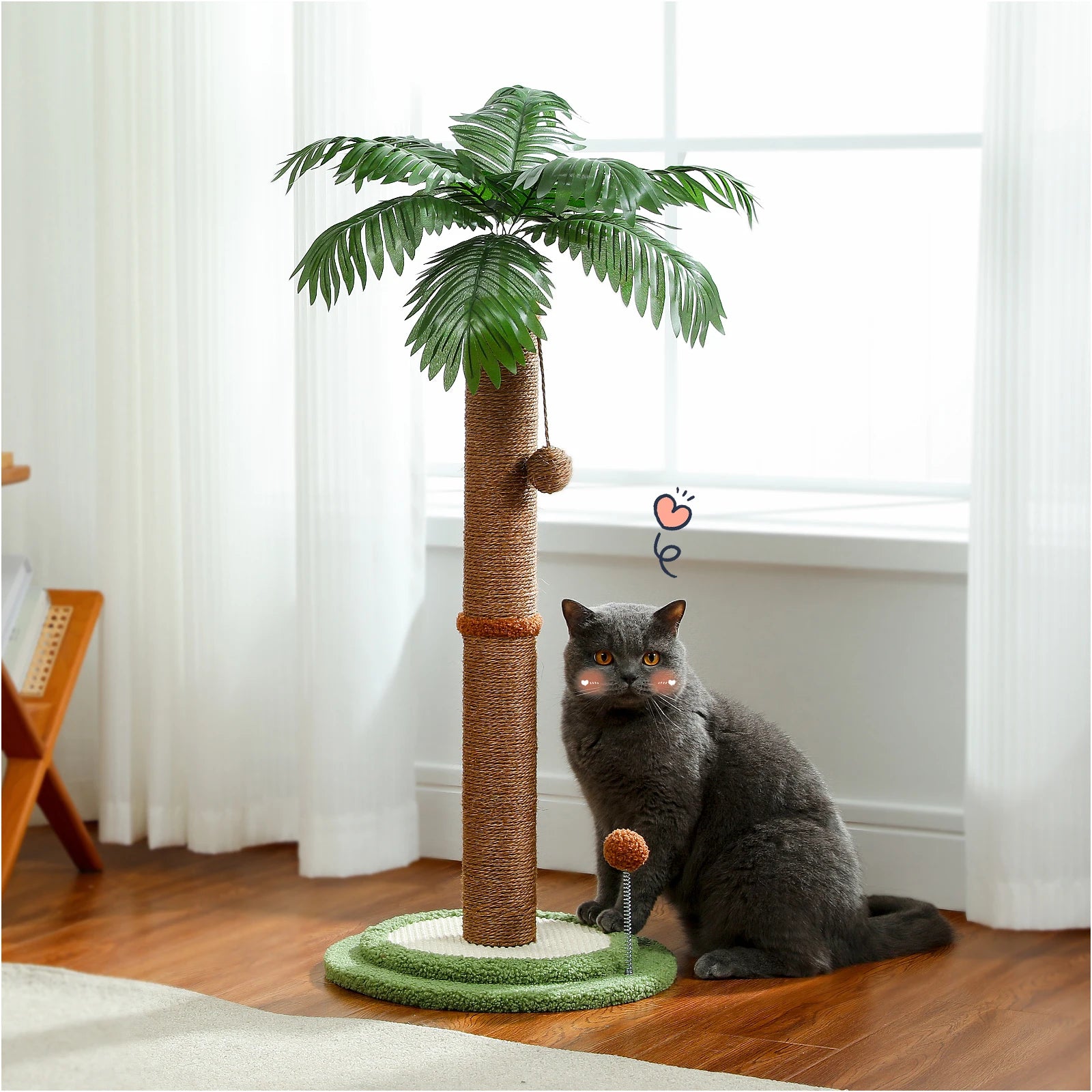 Arbre à chat design palmier tropical avec poteau central en sisal naturel marron, feuilles de palmier réalistes et balles de jeu suspendues, à côté d'un chat gris dans un salon lumineux.