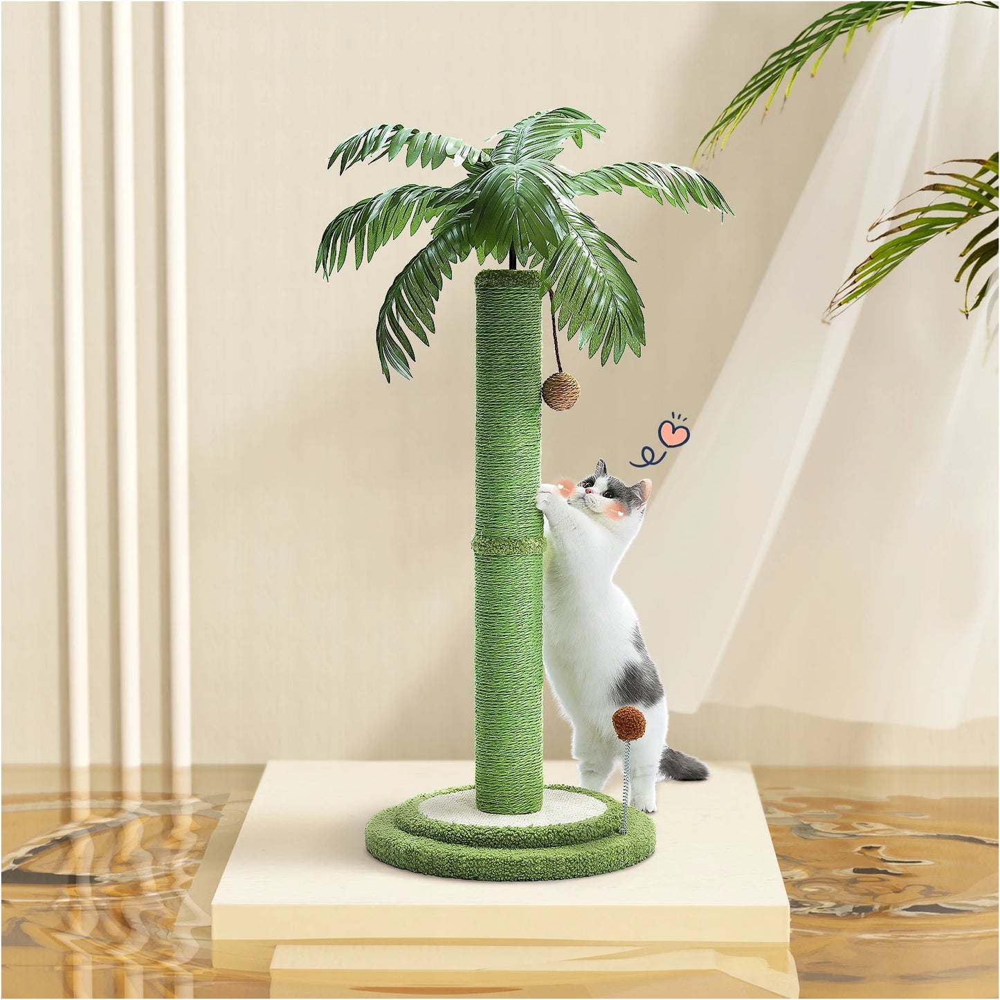 Arbre à chat design palmier avec poteau central en sisal vert, feuilles tropicales réalistes et jouets suspendus, utilisé par un chat blanc et gris dans un intérieur lumineux.