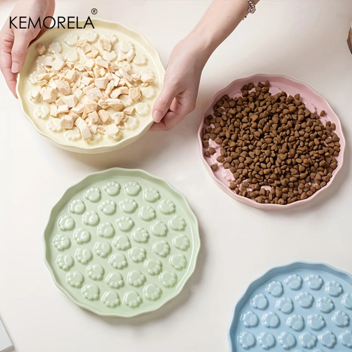 Trois assiettes en céramique crème, rose et verte, l'une garnie de nourriture humide et l'autre de croquettes – Les Trésors d'Owka