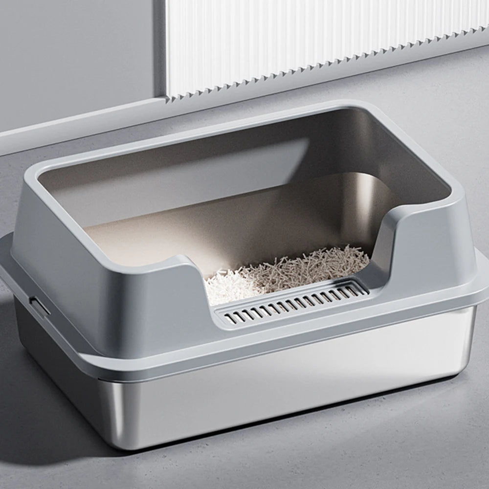 Vue de trois-quarts d'un bac à litière chat haut de gamme avec cuve en acier inoxydable et rebord haut gris mat. Comprend une entrée basse avec grille de nettoyage des pattes, parfait comme bac à litière pour chaton facile d'accès.