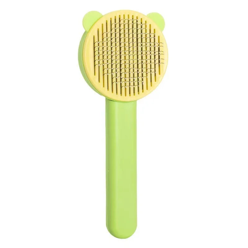 Brosse de toilettage autonettoyante pour chat et chien avec peigne incurvé en acier inoxydable, design oreilles de chat jaune et vert, vue de face sur fond blanc.