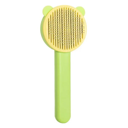 Brosse de toilettage autonettoyante pour chat et chien avec peigne incurvé en acier inoxydable, design oreilles de chat jaune et vert, vue de face sur fond blanc.