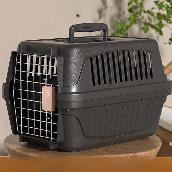 Caisse de transport rigide anthracite pour chat ou petit chien avec porte en grille métallique, système de verrouillage sécurisé à loquet rose et fentes de ventilation latérales.