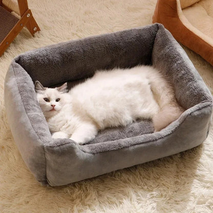 Chat blanc à poils longs allongé dans son canapé pour chat rectangulaire gris avec bords surélevés, intérieur en peluche grise ultra-douce et extérieur en velours résistant.
