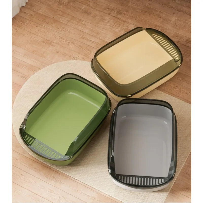 Présentation de trois modèles de bac à litière chat ouverts de couleurs vert olive, jaune crème et gris anthracite, posés sur un tapis. Chaque bac a litiere possède un rebord haut translucide et une grille de sortie intégrée, idéal comme bac à litière pour chaton.