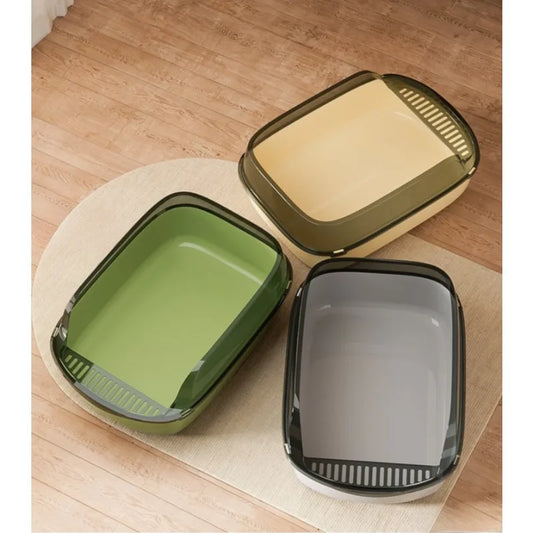 Présentation de trois modèles de bac à litière chat ouverts de couleurs vert olive, jaune crème et gris anthracite, posés sur un tapis. Chaque bac a litiere possède un rebord haut translucide et une grille de sortie intégrée, idéal comme bac à litière pour chaton.