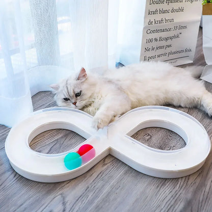Circuit de jeux pour chat interactif en forme de huit blanc. Un chat s'amuse avec les balles intégrées sur un parquet. Ce jouet chat stimule l'éveil et l'instinct de chasse. Jeux chat robuste et design pour occuper votre animal, exclusivité Les Trésors d'Owka.