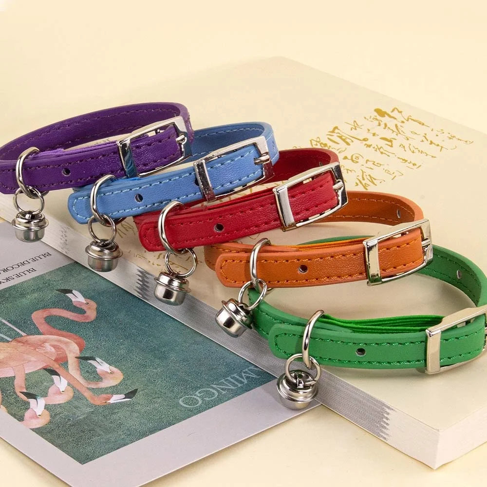 Collection de colliers pour chat en cuir véritable avec surpiqûres, présentant des modèles en bleu ciel, violet, rouge, orange et vert, dotés de boucles métalliques et de grelots.