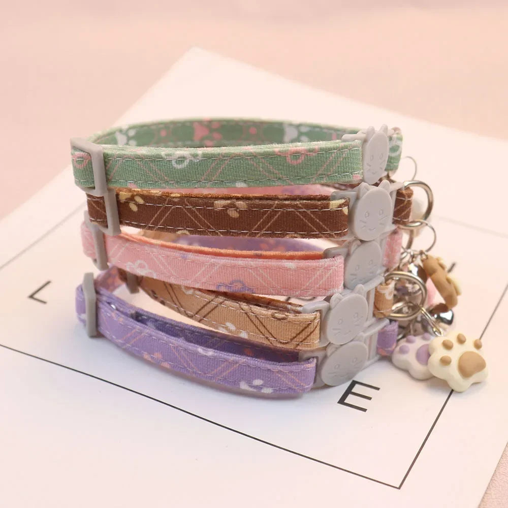 Pile de colliers pour chat aux motifs floraux pastel avec boucle de sécurité anti-étranglement en forme de tête de chat. Chaque collier chaton est muni d'un pendentif patte en silicone et d'une clochette. Ensemble de 5 coloris tendance pour une surveillance sécurisée et élégante des animaux. Les Trésors d'Owka.
