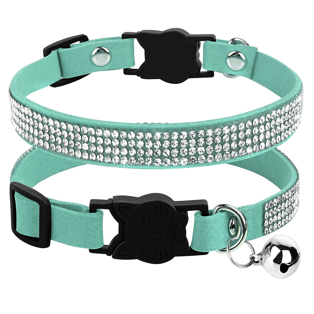 Gros plan d'un collier pour chat en velours bleu menthe orné de trois rangées de strass étincelants, doté d'une boucle de sécurité noire en forme de tête de chat et d'un grelot argenté.