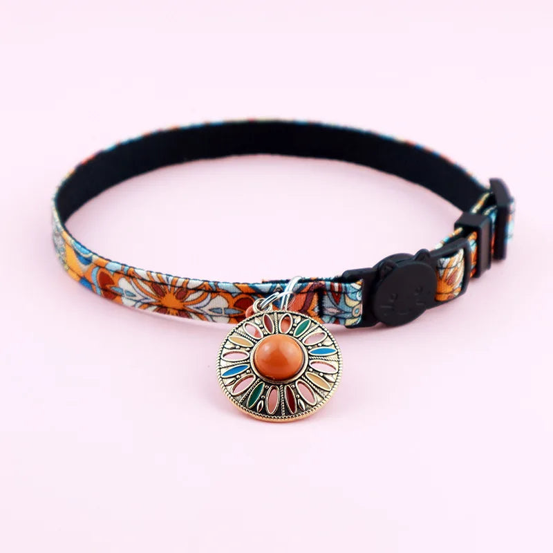Collier pour chat ajustable au motif ethnique orange et floral, avec médaillon mandala serti d'une pierre centrale et fermoir de sécurité tête de chat noir.