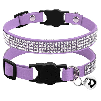 Gros plan d'un collier pour chat en velours violet orné de trois rangées de strass brillants, avec boucle de sécurité noire en forme de tête de chat et grelot argenté.