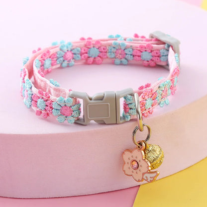 Collier pour chat rose orné de fleurs brodées bleues et roses en relief. Ce collier chaton ajustable comprend un pendentif fleur avec strass et un grelot doré. Accessoire style bohème et chic pour collier chat, idéal pour un look printanier élégant. Finitions artisanales Les Trésors d'Owka.