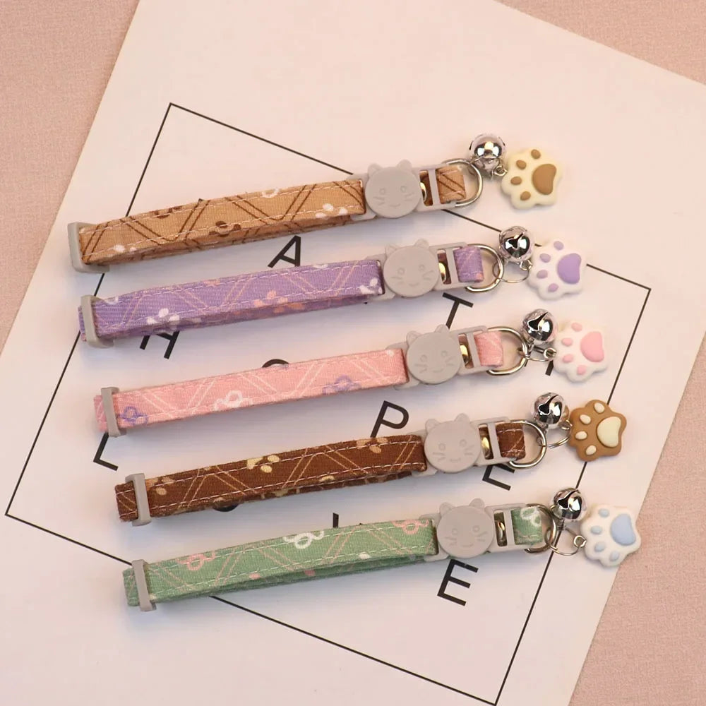 Gamme de 5 colliers pour chat aux couleurs pastel avec motifs japonais. Chaque collier chaton dispose d'une boucle de sécurité en forme de tête de chat, d'une clochette et d'un pendentif patte. Couleurs disponibles : vert, marron, rose, violet et jaune. Accessoire élégant et sécurisé pour animaux. Les Trésors d'Owka.