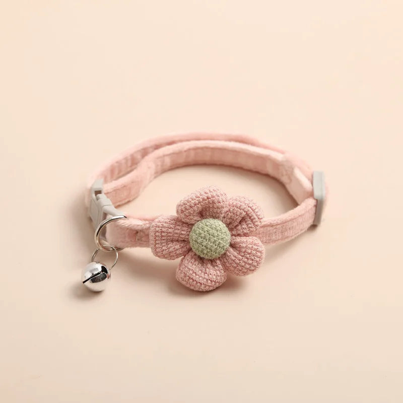 Collier pour chat rose poudré en velours côtelé ultra-doux orné d'une fleur tricotée au cœur vert. Ce collier chaton réglable comprend une clochette argentée et une boucle de sécurité. Accessoire de luxe élégant et confortable pour collier chat au design kawaii. Les Trésors d'Owka.