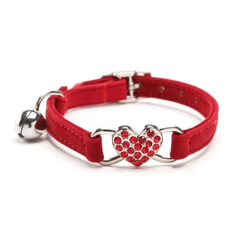 Collier pour chat rouge en velours haut de gamme avec pendentif cœur serti de strass rouges scintillants. Ce collier chaton réglable comprend une boucle argentée robuste et une clochette de sécurité. Accessoire chic et élégant pour petit chat, idéal pour un look sophistiqué. Les Trésors d'Owka.