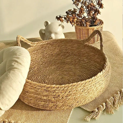 Panier rond pour chat en osier tressé à la main, montrant la base robuste en fibres naturelles et les poignées en forme d'oreilles de chat, style bohème chic.