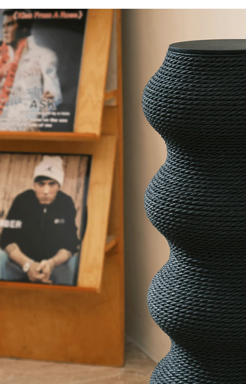 Gros plan sur le tissage serré en corde noire haute densité d'un poteau à griffer sculptural pour chat, montrant la texture robuste et les finitions premium du sommet.