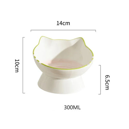 Fiche technique d'une gamelle pour chat en céramique blanche de 300 ml avec dimensions : 14 cm de large, 10 cm de haut et base surélevée à 6,5 cm. Cette gamelle chat surélevée au design de tête de chat avec liseré vert assure une hygiène parfaite et un confort ergonomique. Une gamelle robuste et élégante pour un repas sain.