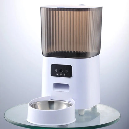 Vue de face d'un distributeur croquettes chat et chien blanc avec réservoir fumé et gamelle en acier inoxydable. Le visuel montre le panneau de contrôle LCD pour la programmation des repas. Ce distributeur croquettes automatique assure une conservation parfaite et une hygiène optimale. Idéal comme distributeur croquettes chien compact et fiable pour une alimentation maîtrisée.