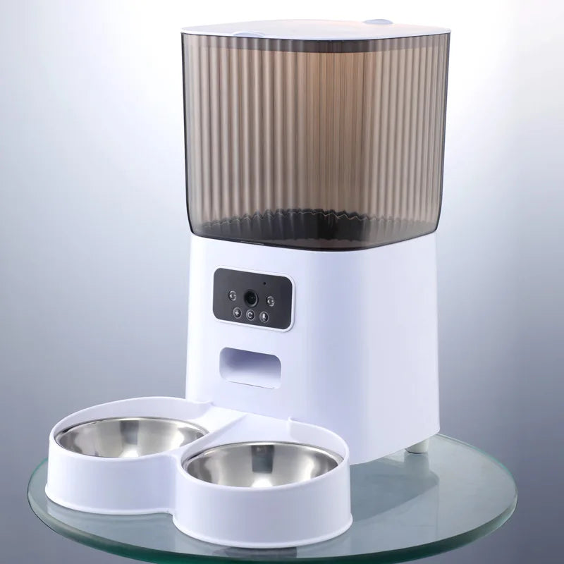 Vue de face d'un distributeur croquettes chat et chien blanc avec caméra HD et double gamelle en acier inoxydable. Le visuel montre le panneau de contrôle intelligent et le réservoir fumé strié. Ce distributeur croquettes automatique Wi-Fi permet de nourrir et de filmer deux animaux simultanément. Idéal comme distributeur croquettes chien intelligent pour une gestion alimentaire connectée et équitable.