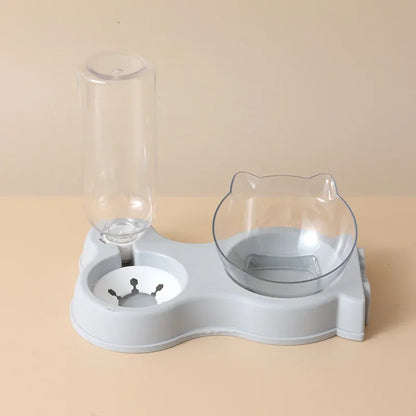 Station de nutrition 2-en-1 gris scandinave avec distributeur croquettes chat incliné et réserve d'eau automatique. Le visuel montre le bol transparent design oreilles de chat et la bouteille d'eau par gravité. Ce distributeur croquettes manuel offre un confort cervical optimal. Idéal comme distributeur croquettes chien miniature pour un intérieur moderne et épuré.