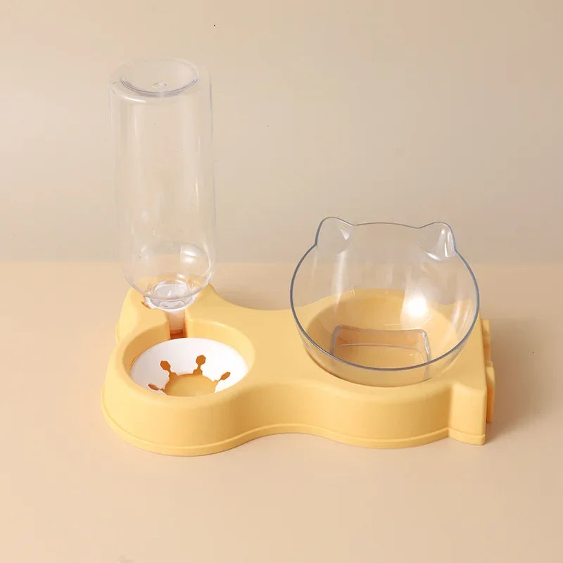 Station de nutrition 2-en-1 jaune pastel avec distributeur croquettes chat incliné et réserve d'eau automatique. Le visuel montre le bol transparent design oreilles de chat et le flacon réservoir par gravité. Ce distributeur croquettes manuel offre un confort cervical optimal pour l'animal. Idéal comme distributeur croquettes chien de petite taille pour une maison moderne.