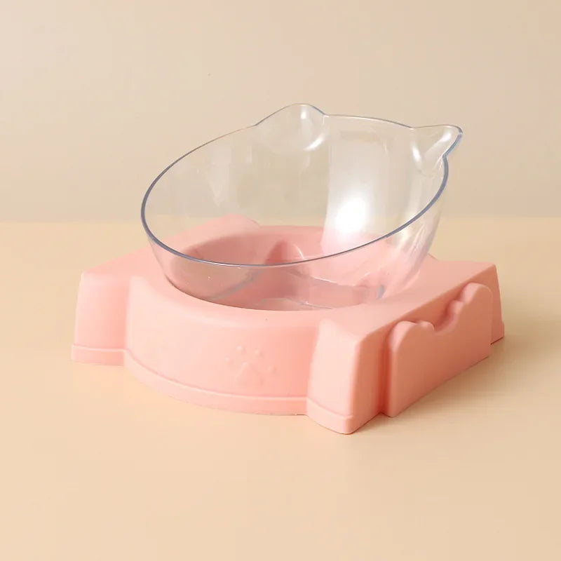 Vue de profil d'un distributeur croquettes chat orthopédique avec bol transparent incliné et socle rose pastel. Le visuel montre le design oreilles de chat et l'inclinaison ergonomique pour le confort cervical. Ce distributeur croquettes manuel aide à prévenir les reflux. Parfait comme distributeur croquettes chien miniature pour une alimentation saine et élégante.