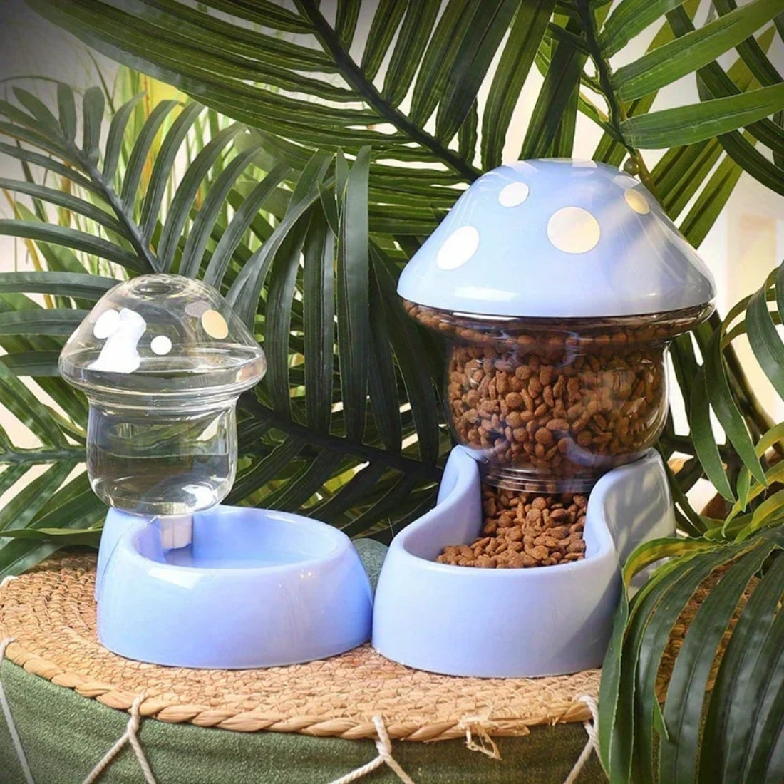 Ensemble assorti de distributeurs d'eau et de croquettes pour chat bleu ciel en forme de champignon, présentés dans un décor tropical avec plantes vertes et socle en osier.