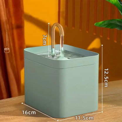 Fontaine à eau pour chat rectangulaire vert sauge avec bec verseur type robinet transparent, dimensions 16 cm par 11,5 cm et hauteur totale de 19,5 cm.