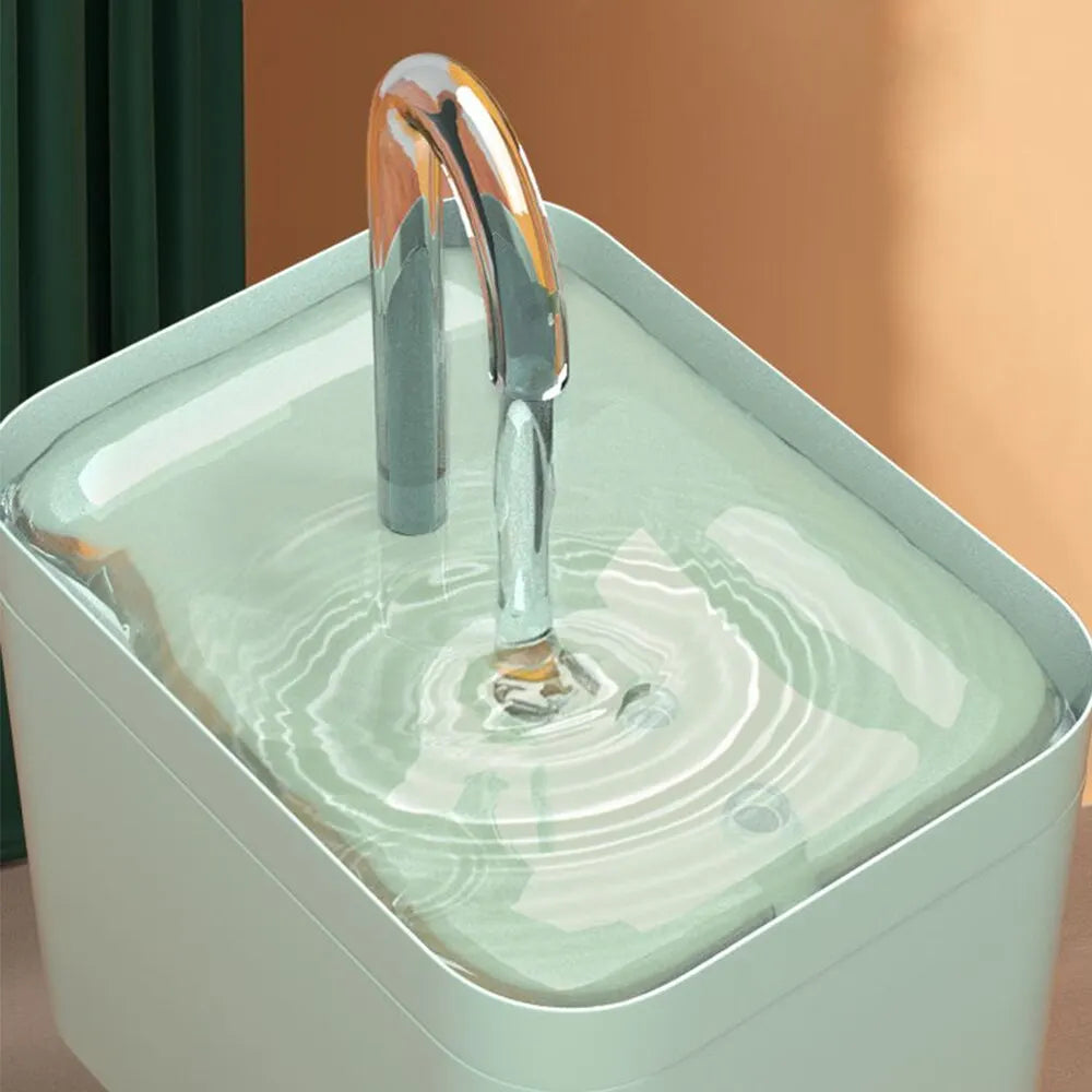 Gros plan d'une fontaine à eau pour chat vert menthe avec un bec verseur type robinet transparent diffusant un flux d'eau limpide et continu dans un réservoir épuré.