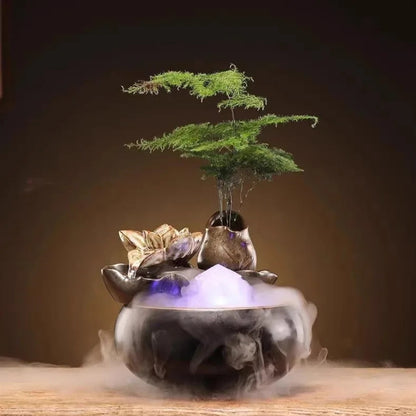 Fontaine zen en céramique sculptée avec cascade fleur de lotus, brumisateur ultrasonique créant une fumée épaisse, éclairage LED violet et pot intégré avec plante décorative.