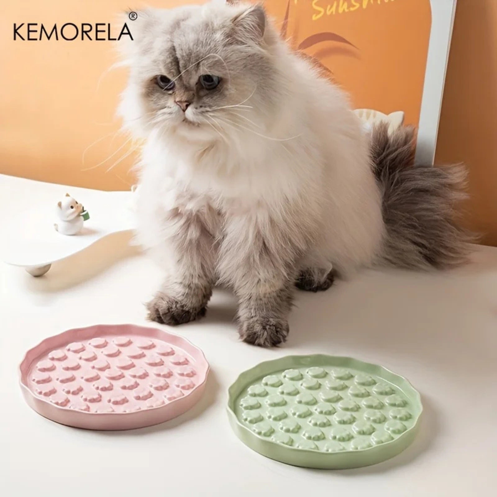 Chat à poils longs utilisant une gamelle anti glouton chat en céramique design de marque Kemorela. La photo présente trois modèles de gamelle glouton aux couleurs pastel (rose, bleu, beige) remplis de croquettes et de nourriture humide. Cette gamelle anti glouton permet de ralentir la prise alimentaire du chat pour une meilleure digestion et éviter les vomissements.