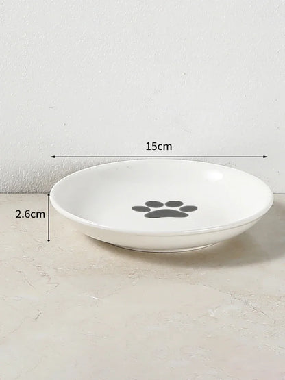 Gamelle pour chat en céramique blanche de 15 cm de diamètre et 2,6 cm de profondeur, avec motif patte de chat grise au centre, idéale pour prévenir la fatigue des moustaches.
