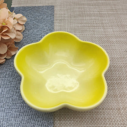Gamelle pour chat en céramique jaune citron brillant en forme de fleur, design évasé et peu profond pour prévenir la fatigue des moustaches, présentée sur un tapis de table texturé.