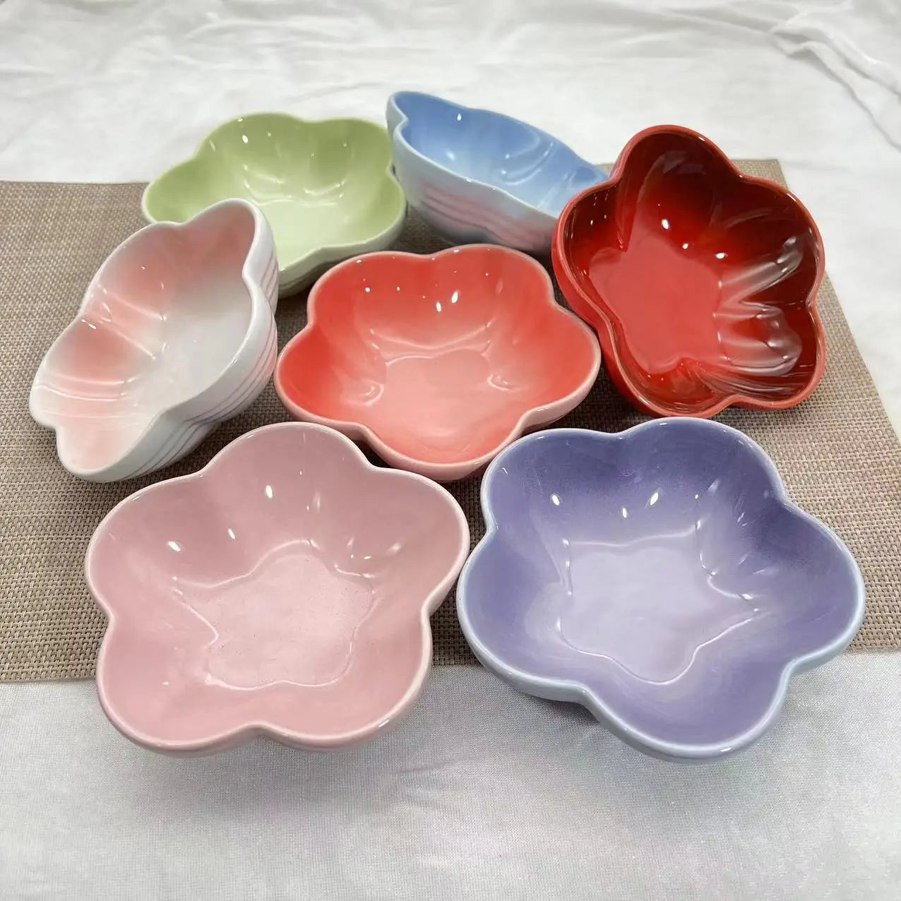 Collection de gamelles pour chat en céramique en forme de fleur, disponibles en plusieurs coloris pastel et vifs : rose, violet, rouge, corail, bleu, vert et blanc dégradé.