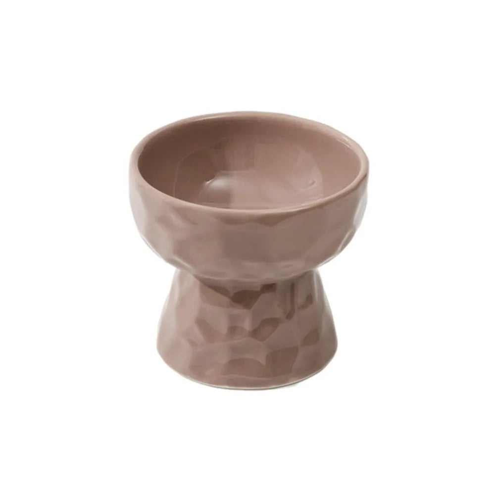 Gamelle pour chat surélevée en céramique taupe avec texture martelée facettée et fini brillant. Cette gamelle animaux ergonomique offre une hauteur de 11 cm pour une posture de repas saine et confortable. Une gamelle chat haut de gamme, stable et facile à nettoyer, idéale pour un intérieur moderne et le bien-être de votre félin.