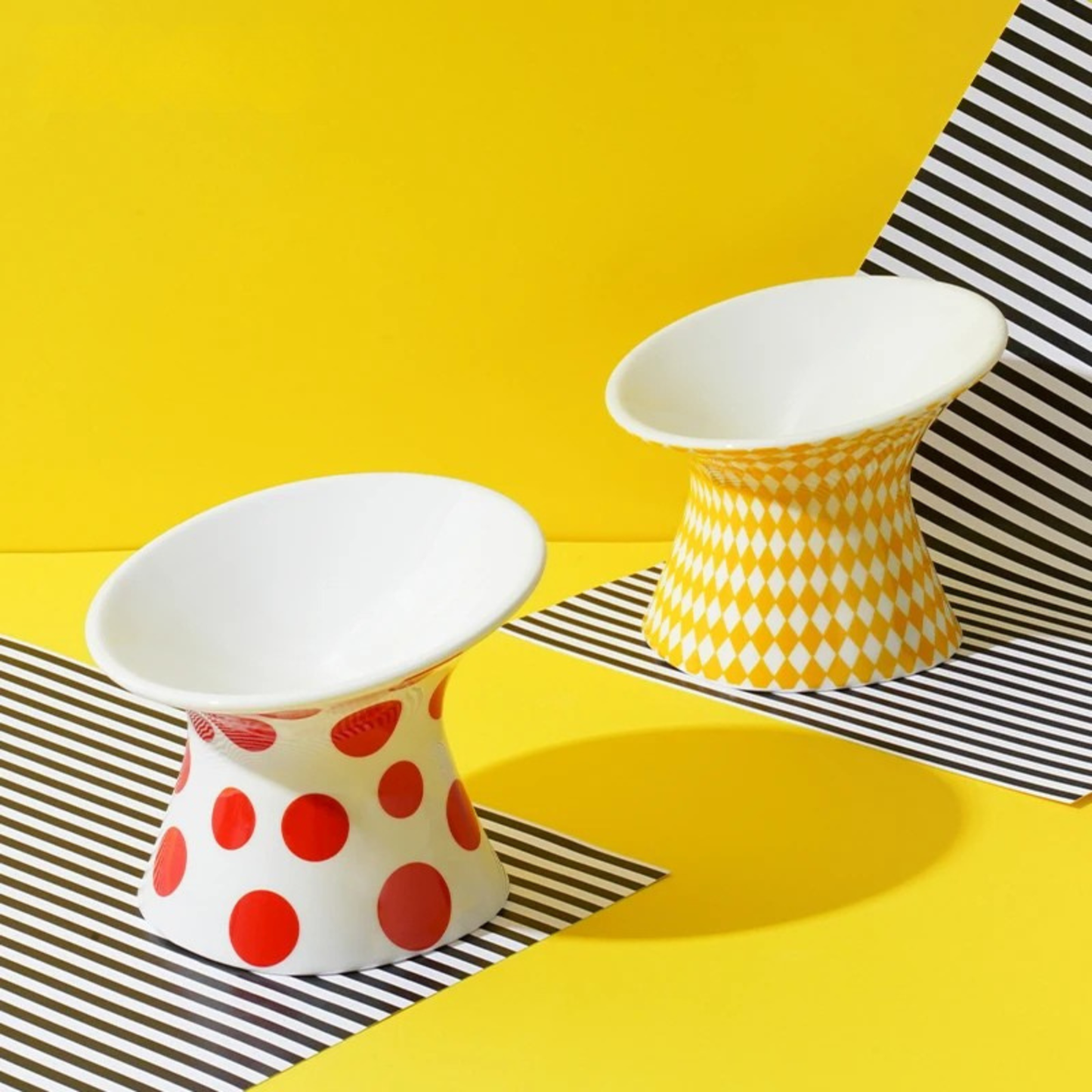 Collection Zeze de gamelles pour chat surélevées en céramique avec motifs à pois rouges et losanges jaunes. Cette gamelle animaux ergonomique et inclinée protège les cervicales et facilite la digestion de votre félin. Une gamelle pour chat de luxe, stable et hygiénique, idéale pour un intérieur moderne et coloré.