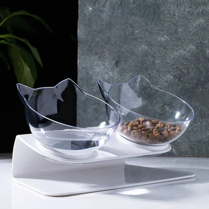 Gamelle pour chat double inclinée à 15 degrés avec deux bols transparents design oreilles de chat sur support blanc ergonomique. Cette gamelle chat orthopédique de luxe assure un confort cervical optimal, protège la colonne vertébrale et facilite la digestion de votre félin. Une gamelle élégante et moderne pour un coin repas sain et ordonné.