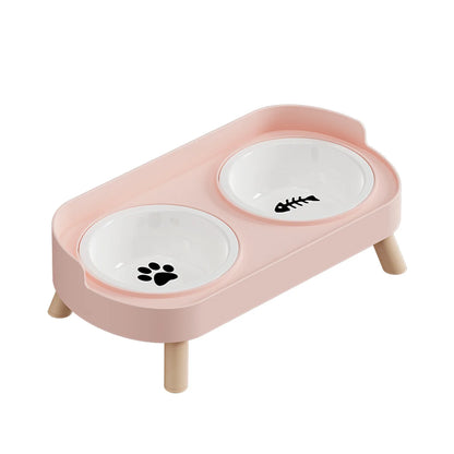 Gamelle pour chat double surélevée au design scandinave rose poudré avec bols amovibles en céramique blanche et pieds en bois clair. Cette gamelle chat orthopédique décorée d'une patte et d'une arête de poisson assure un confort cervical optimal et une hygiène parfaite. Une gamelle duo robuste et élégante aux finitions premium pour votre animal."