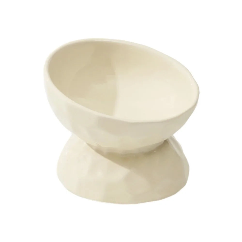 Gamelle pour chat surélevée et inclinée en céramique beige ivoire avec texture martelée et fini brillant. Cette gamelle animaux ergonomique protège les cervicales et facilite la digestion grâce à son angle de 15 degrés. Une gamelle chat haut de gamme, stable et facile à nettoyer pour un confort alimentaire optimal.