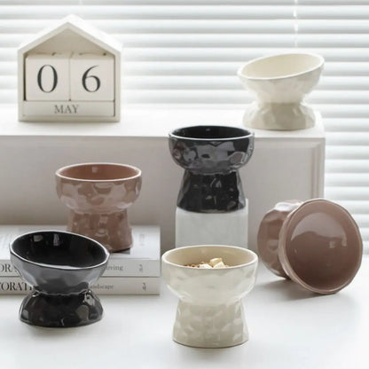 Collection de gamelles pour chat surélevées et inclinées en céramique design, disponibles en noir, beige et taupe. Cette gamelle animaux ergonomique prévient les douleurs cervicales et facilite la digestion. Une gamelle chat moderne au fini brillant et texture martelée, idéale pour une décoration d'intérieur raffinée et le confort de votre félin.