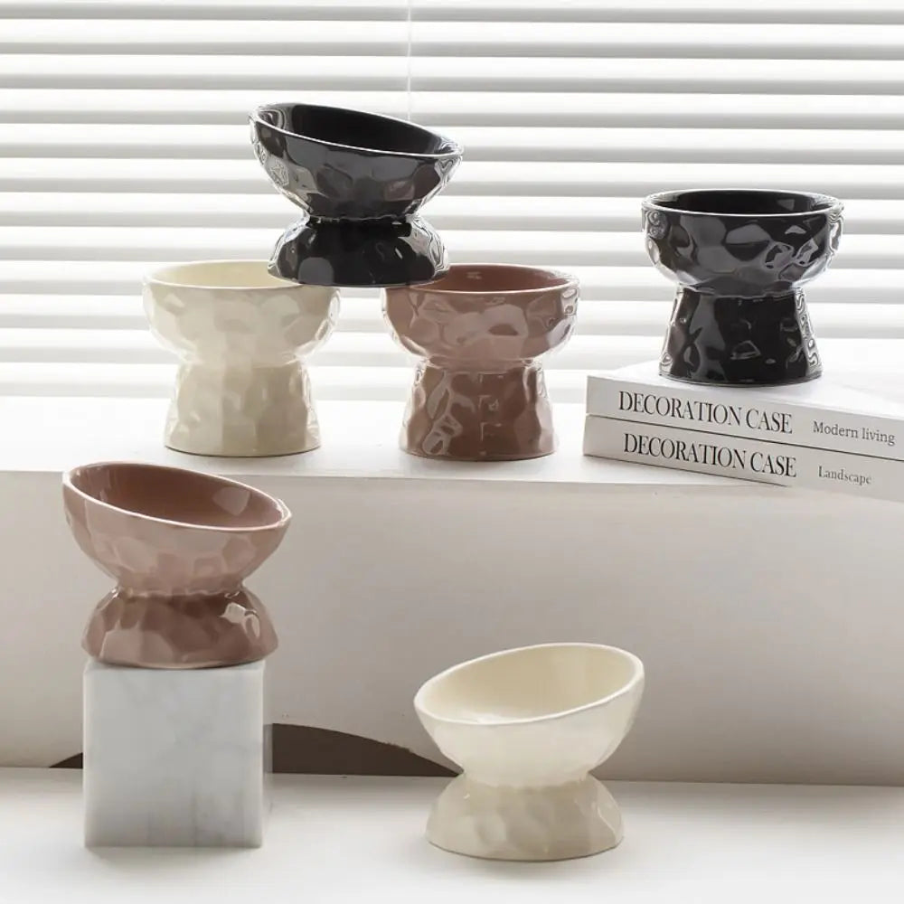 Collection de gamelles pour chat surélevées et inclinées en céramique design, disponibles en noir, beige et taupe. Cette gamelle animaux ergonomique prévient les douleurs cervicales et facilite la digestion. Un gamelle chat moderne au fini brillant et texture martelée, idéale pour une décoration d'intérieur raffinée et le confort de votre félin.