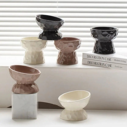 Collection de gamelles pour chat surélevées et inclinées en céramique design, disponibles en noir, beige et taupe. Cette gamelle animaux ergonomique prévient les douleurs cervicales et facilite la digestion. Un gamelle chat moderne au fini brillant et texture martelée, idéale pour une décoration d'intérieur raffinée et le confort de votre félin.