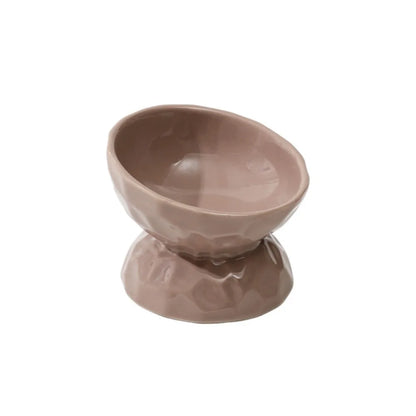 Gamelle pour chat surélevée et inclinée en céramique taupe avec texture martelée et fini brillant. Cette gamelle animaux ergonomique protège les cervicales et facilite la digestion grâce à son angle de 15 degrés. Une gamelle chat haut de gamme, stable et facile à nettoyer pour un confort alimentaire optimal.