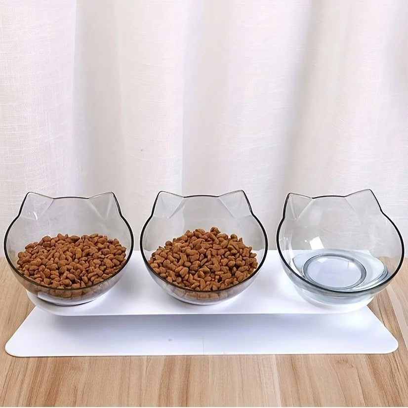 Station de nourriture triple avec gamelle pour chat transparente en forme d'oreilles de chat. Le support blanc surélevé et incliné à 15° offre une position ergonomique pour protéger les cervicales. Cette gamelle chat triple permet de séparer l'eau, les croquettes et la pâtée. Un ensemble gamelle chaton design et anti-vomi idéal pour une digestion optimale et un intérieur moderne.
