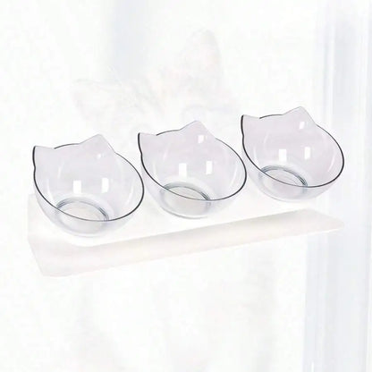 Station de repas triple avec gamelle pour chat transparente en polycarbonate cristal. Le support blanc incliné à 15 degrés offre une position ergonomique qui protège les cervicales de l'animal. Cette gamelle chat triple au design d'oreilles de chat est facile à nettoyer et anti-vomi. Un ensemble gamelle chaton minimaliste et esthétique pour un intérieur moderne.