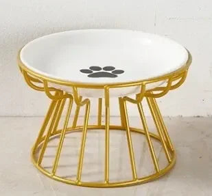 Gamelle surélevée pour chat avec bol en céramique blanche orné d'un motif patte, posé sur un support ergonomique en métal doré au design moderne et stable.